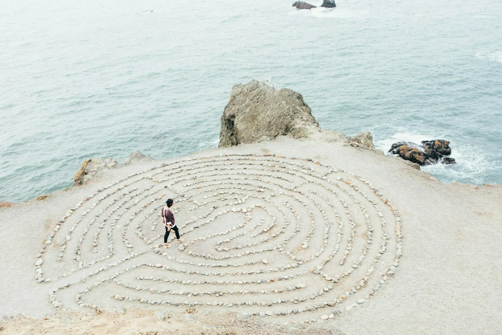 person holding compass facing towards green pine trees